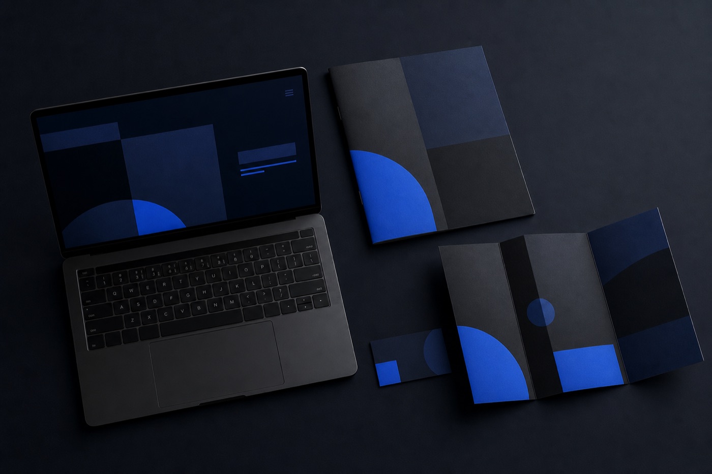 A premium flat lay of a laptop showing a website next to printed brand materials, representing digital and print services