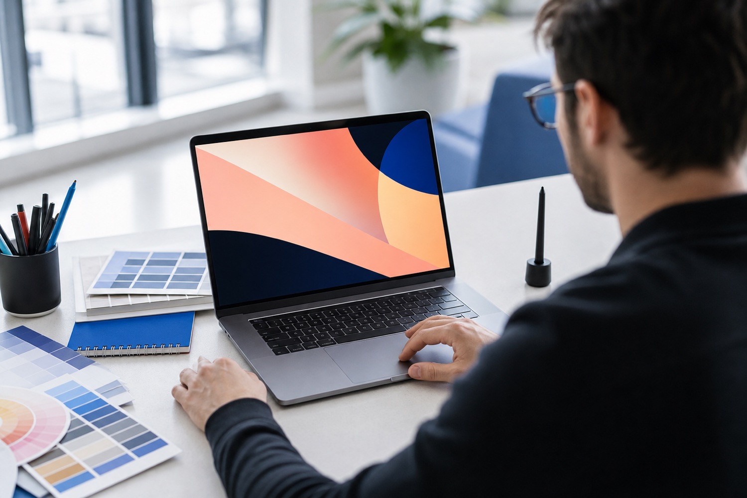 A designer working on brand visuals with colour swatches on a light desk